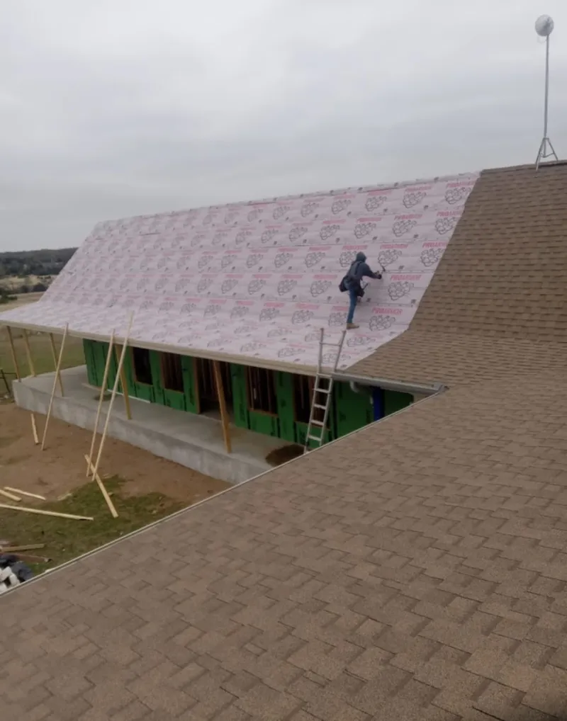 Worker preparing underlayment for a metal roof installation in Milford